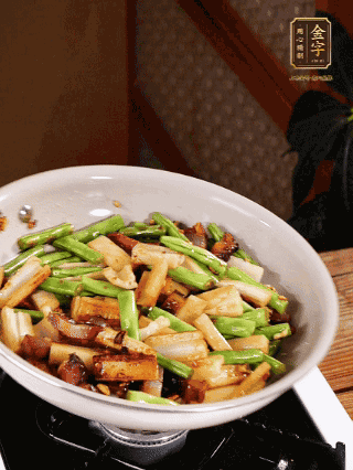 油熱下蒜末、干辣椒、醬肉煸炒出香味，依次下藕條、豆角翻炒均勻
