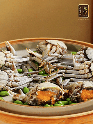 盤(pán)底鋪毛豆，依次放大閘蟹、咸肉， 淋一圈料酒、豉油。